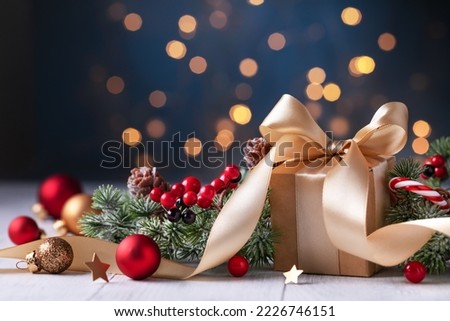 Christmas gift or present box, snowy fir tree and holiday decoration against magic blue bokeh background. New year greeting card.