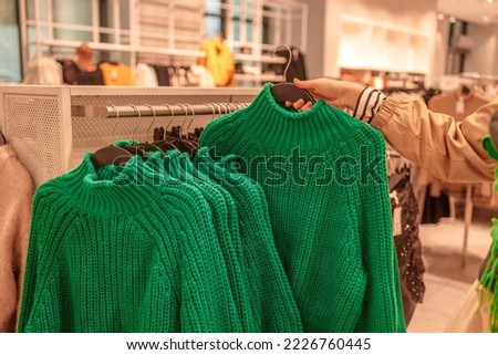 Warm sweaters on a wardrobe hanger on a light background. Autumn, winter clothes. Shopping store. Gdansk, Poland, Europe. 