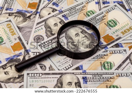 Hundred dollar banknote under magnifying glass 