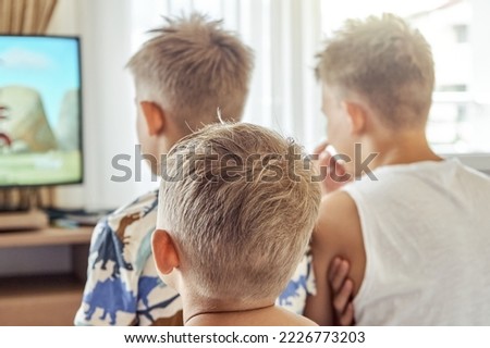 Brothers sitting in hotel room watch cartoons on TV