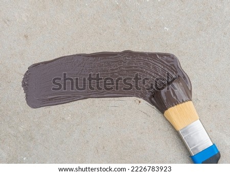 a brush with brown paint and a trace of the brush on the concrete panel. copy space.