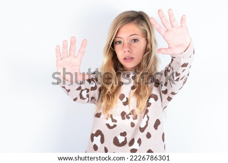 Portrait of smiling caucasian teen girl wearing animal print sweater over white background looking at camera and gesturing finger frame. Creativity and photography concept.