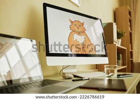 Focus on computer screen with graphic picture of fat and fluffy ginger cat on white background drawn by modern digital artist