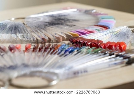 Nail swatch sticks with metal rings on wooden table. Fan-shaped plastic palettes tips for demonstration in manicure salon extreme closeup