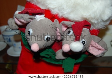Two stuffed mice wearing a red Christmas hat with a white ball