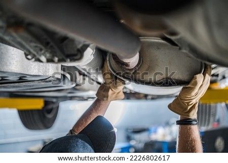 Mechanic Inspecting Vehicle's Catalytic Converter During Scheduled Car Exhaust System Check. Automobile Maintenance Theme. Royalty-Free Stock Photo #2226802617