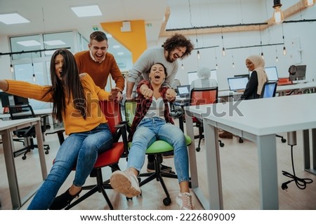 Team building and office fun. Young cheerful businesspeople in smart casual wear having fun while racing on office chairs and smiling. Royalty-Free Stock Photo #2226809009