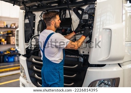 Professional truck mechanic working in vehicle repair service. Royalty-Free Stock Photo #2226814395