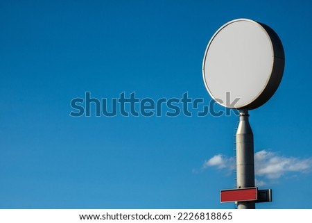 little red rectangular sign and circle white lightbox pole sign with blue sky background