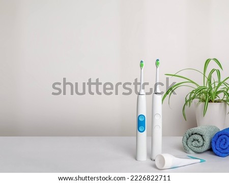 Two electric toothbrushes, toothpaste, two towels and a flower.