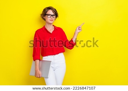 Photo of nice confident girl with bob hairstyle wear red shirt hold laptop indicating empty space isolated on yellow color background