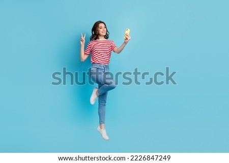Full length photo of charming positive blogger make self picture send followers flying air hand v-sign isolated on blue color background