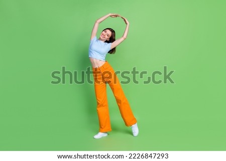 Full size portrait of stunning satisfied girl raise hands toothy smile isolated on green color background