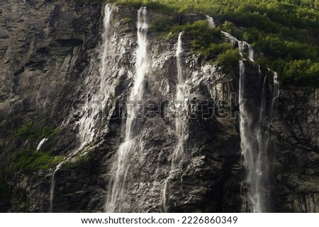 Picture of the Seven Sister Waterfall located in the Geiranger fjord in Norway. The photo was captured on the edge of a creeing sunset. The majestic landscapes of the fjord makes up the backdrop. 