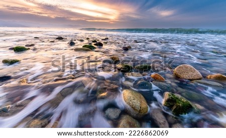 A Closeup Low Angle View of Ocean Rocks and A Wave In The Background In 16.9 Image Format Royalty-Free Stock Photo #2226862069