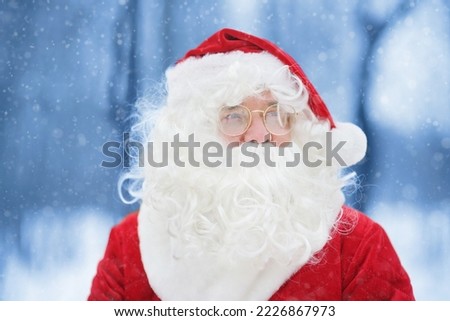 Close-up portrait of Santa Claus in a snowy winter forest. Animator or parent in Santa Claus costume is rushing to a holiday for children. Traditions of Christmas holidays. St. Nicholas Day.