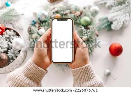 Phone with an isolated screen on the background of a Christmas wreath, the concept of a festive master class