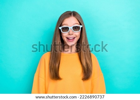 Photo of young teenager girl wear orange sweatshirt excited wear 3d goggles watching film excited isolated on aquamarine color background