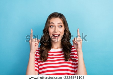 Photo of sweet excited lady wear striped t-shirt pointing two fingers empty space isolated blue color background