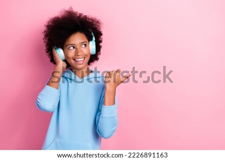 Photo portrait of charming school girl earphones point look empty space promo dressed stylish blue outfit isolated on pink color background