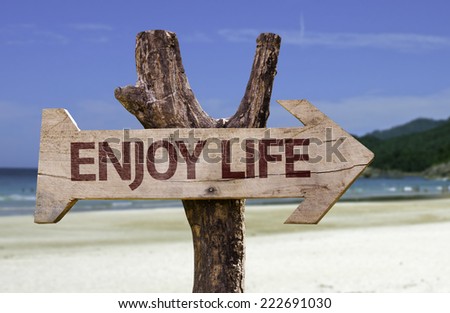 Enjoy Life wooden sign with a beach on background