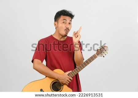Portrait of Young Asian man in red t-shirt with an acoustic guitar isolated on white background. Music, entertainment and hobby concept.