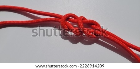 red rope knot isolated on a white background as a strong nautical marine line tied together as a symbol for trust and faith ,infinity shape