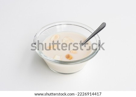 A bowl of plain oat yogurt topped with sliced almonds isolated on a white background. Non-dairy full-fat yogurt alternative.