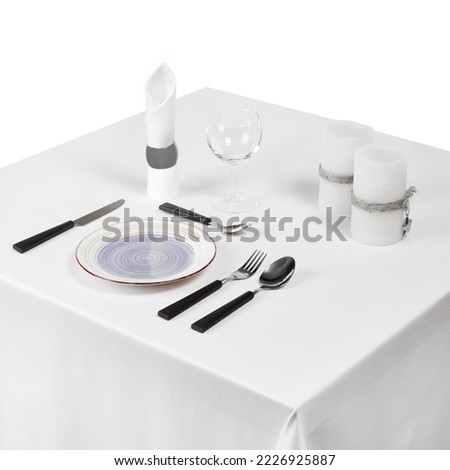 Square restaurant table setup with plate and cuttlery, candles and empty glass ready to serve isolated on white