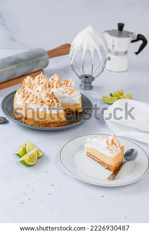 photography of a lemon pie along with a slice on a marble table