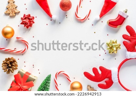 Bright Christmas flatlay frame of holiday decorations on white background with copy space in the middle. Top view
