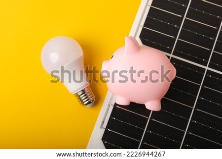 Flat lay composition with solar panel, led lamp and piggy bank on yellow background. The concept of saving money and clean energy. The concept of ecology and sustainable development. Royalty-Free Stock Photo #2226944267