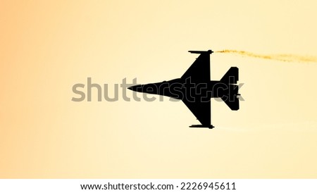 Silhouette of fighter plane flying against sunlight  Royalty-Free Stock Photo #2226945611