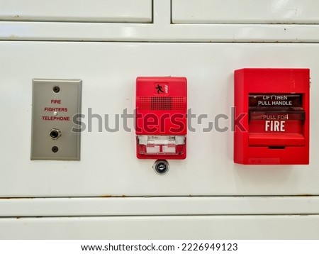 set of fire extinguishers on the hospital wall.  alarms, telephones, and fire-fighting trigger levers