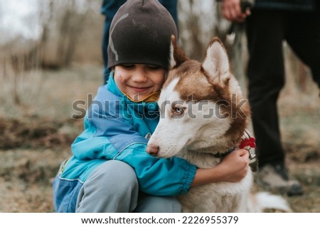 kid and his friend husky siberian dog. portrait little child boy hugging cute white brown mammal animal pet of one year old with blue eyes in autumn rustic and countryside nature forest