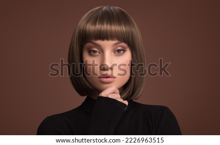 Portrait of a beautiful brunette girl with a short haircut. Brown background. Royalty-Free Stock Photo #2226963515
