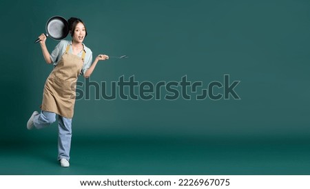 Asian woman wearing apron and holding a pan Royalty-Free Stock Photo #2226967075