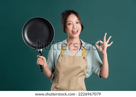 Asian woman wearing apron and holding a pan Royalty-Free Stock Photo #2226967079