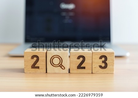 2023 block with magnifying glass icon against laptop background. Hiring, recruitment, job, jobless SEO, Search Engine Optimization and New Year concepts