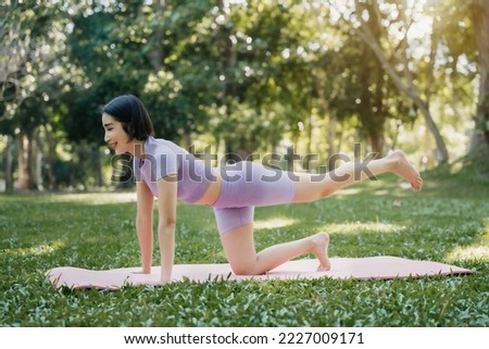 Asian woman relaxing in yoga pose in park.