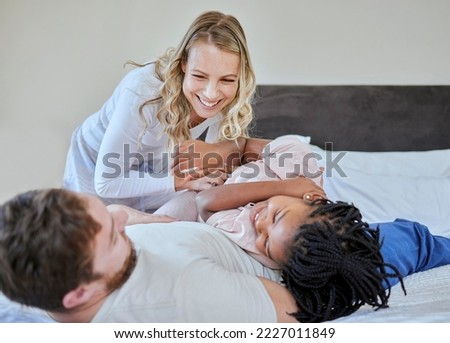 Foster parents tickle adoption kid in bedroom, family home and house for fun, bonding and quality time with love, care and happiness together. Happy black kid relax with mom, dad and diversity people Royalty-Free Stock Photo #2227011849