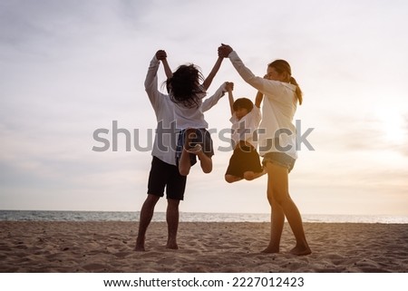 Happy asian family jumping together on the beach in holiday vacation. Silhouette of the family holding hands enjoying the sunset on the sea beach. Happy family travel, trip  family holidays weekend. Royalty-Free Stock Photo #2227012423