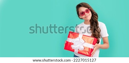 fashionable happy kid in sunglasses hold gift box, birthday. Kid girl with gift, horizontal poster. Banner header with copy space.