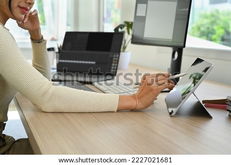 Cropped shot of female content creator using digital tablet and laptop computer at modern office