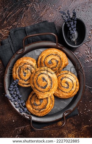 Sweet twisted Bun with poppy seeds and lavender. Dark background. Top view.