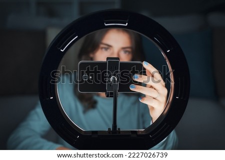 Influencer girl creating videos for social media at home, she is using a smartphone and a ring light Royalty-Free Stock Photo #2227026739