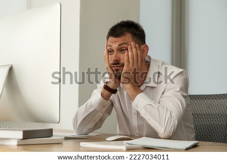 Sleep deprived man at workplace in office Royalty-Free Stock Photo #2227034011