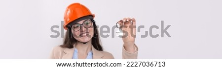 A girl in a construction helmet holds a house. Realtor on a white background.