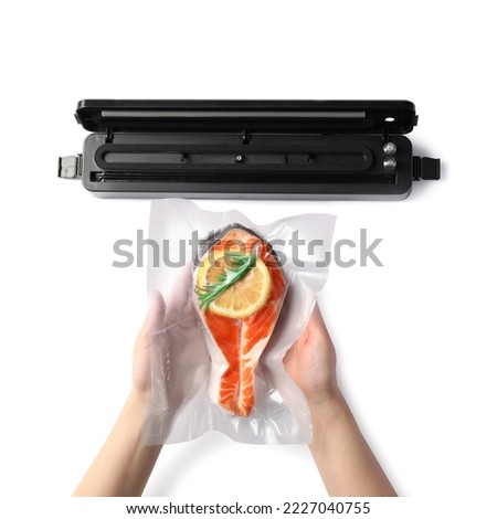 Woman using vacuum sealer on white background, top view. Salmon with lemon in pack Royalty-Free Stock Photo #2227040755