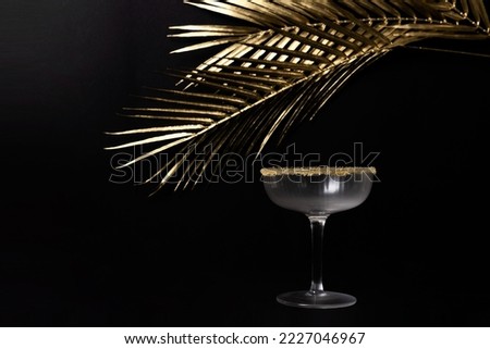 Elegant and classy picture of a cocktail glass with golden leaves against the bakcground. Festive background, no people. 